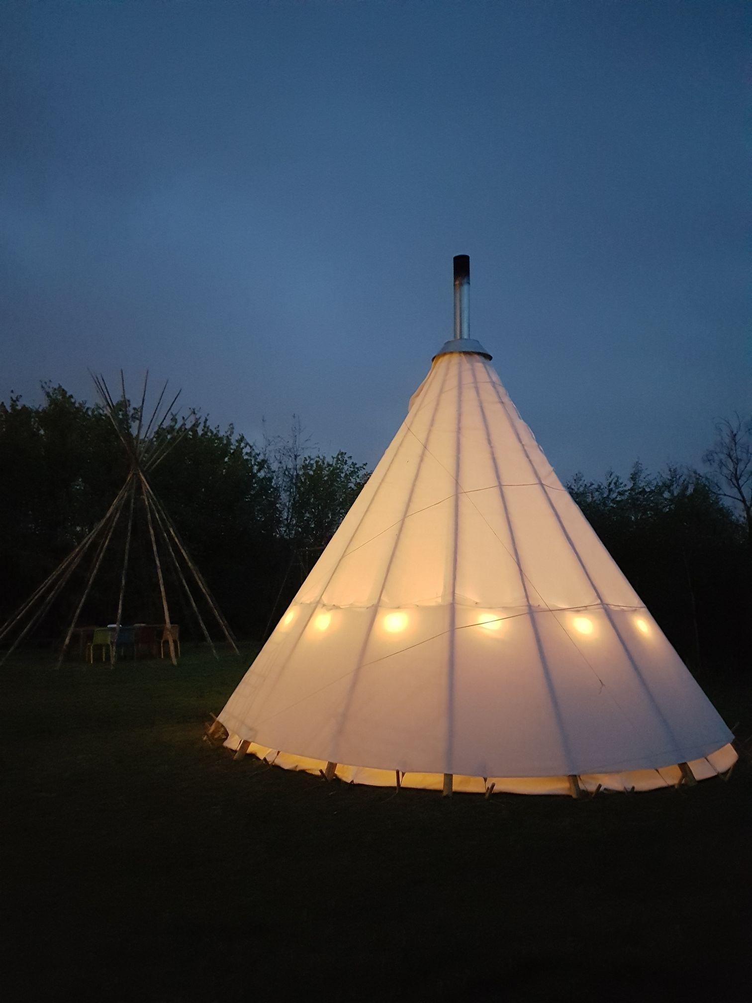 Tipi met schoorsteen en Woodchuck tuinkachel bij schemer