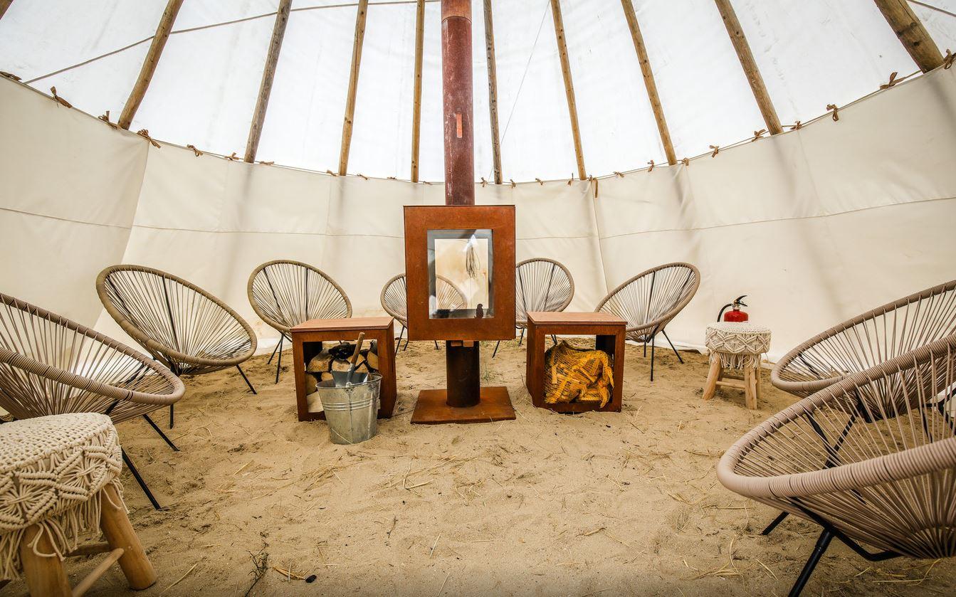 Woodchuck Tipi met houtkachel op het strand met inrichting